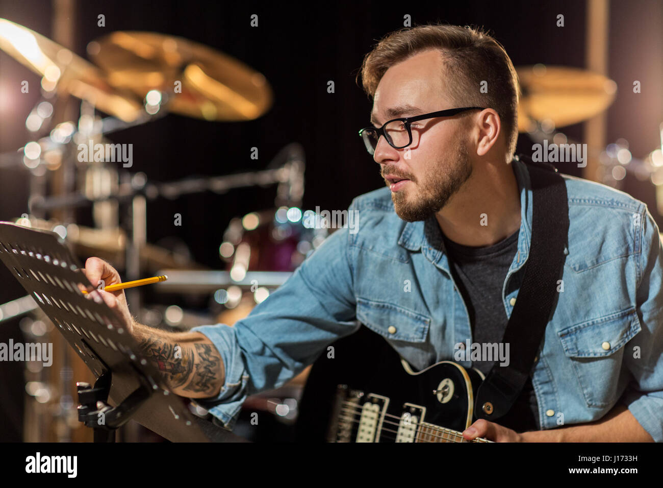 Man with guitar écrit au livre de la musique au studio Banque D'Images