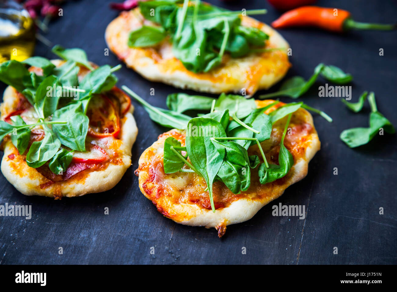 Mini pizzas bruschettas ou avec du fromage, salami et feuilles d'épinards frais Banque D'Images