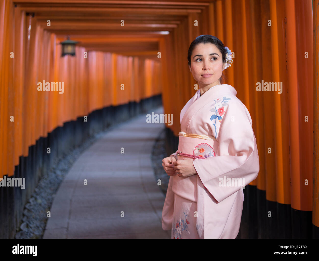 Jeune japonaise en kimono marcher à travers le tunnel de Torri gates au Sanctuaire Fushimi Inari, Kyoto, Japon Banque D'Images