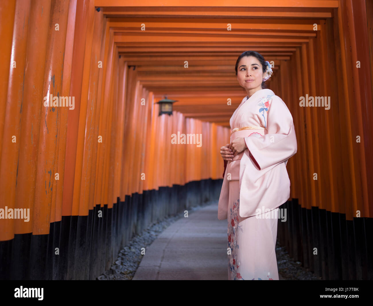 Jeune japonaise en kimono marcher à travers le tunnel de Torri gates au Sanctuaire Fushimi Inari, Kyoto, Japon Banque D'Images
