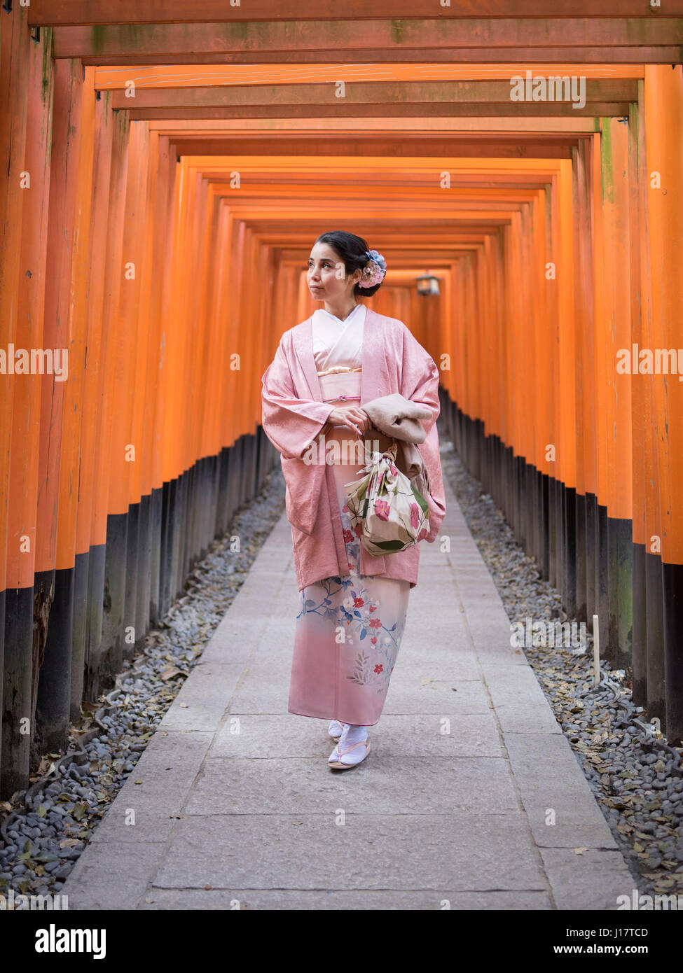 Jeune japonaise en kimono marcher à travers le tunnel de Torri gates au Sanctuaire Fushimi Inari, Kyoto, Japon Banque D'Images