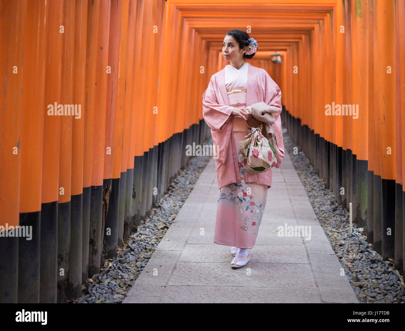 Jeune japonaise en kimono marcher à travers le tunnel de Torri gates au Sanctuaire Fushimi Inari, Kyoto, Japon Banque D'Images