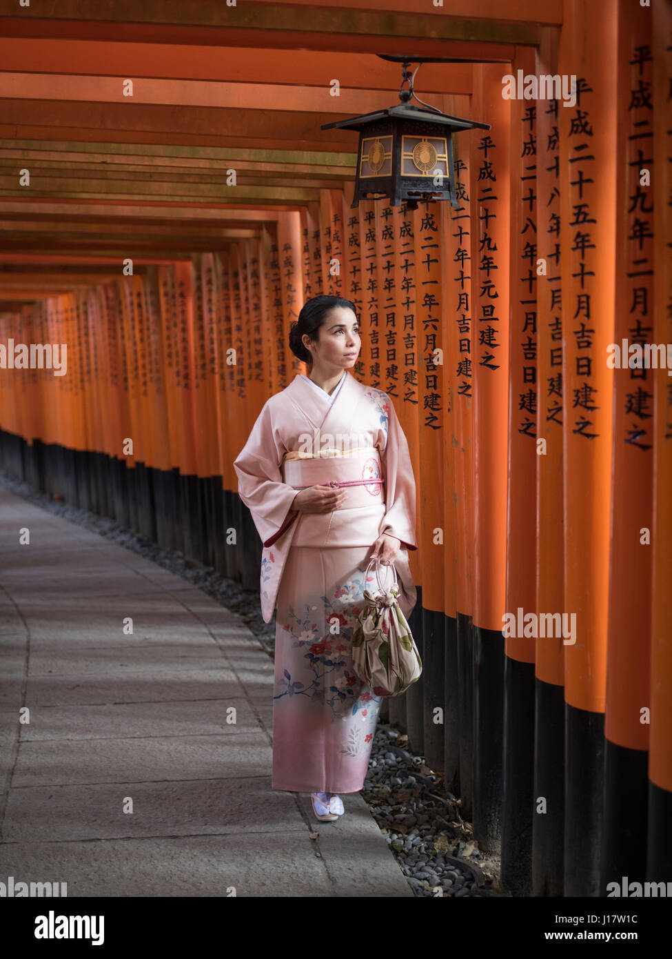Jeune japonaise en kimono marcher à travers le tunnel de Torri gates au Sanctuaire Fushimi Inari, Kyoto, Japon Banque D'Images