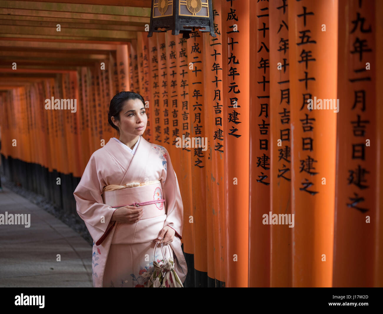 Jeune japonaise en kimono marcher à travers le tunnel de Torri gates au Sanctuaire Fushimi Inari, Kyoto, Japon Banque D'Images