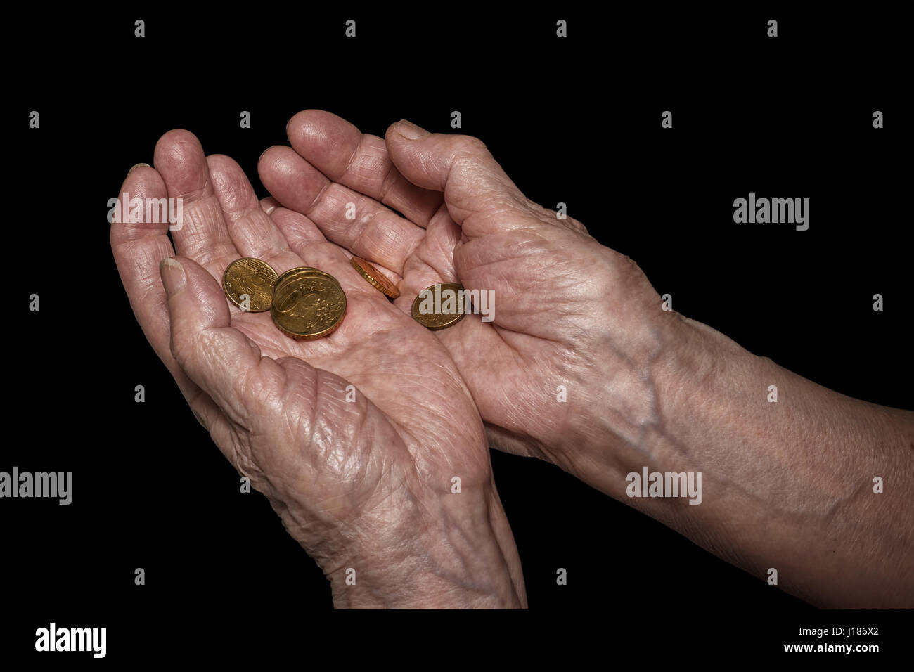 Senior woman hands holding quelques pièces en euros. Pension, la pauvreté, les problèmes sociaux et la sénilité thème. Isolé sur noir, chemin de détourage inclus Banque D'Images