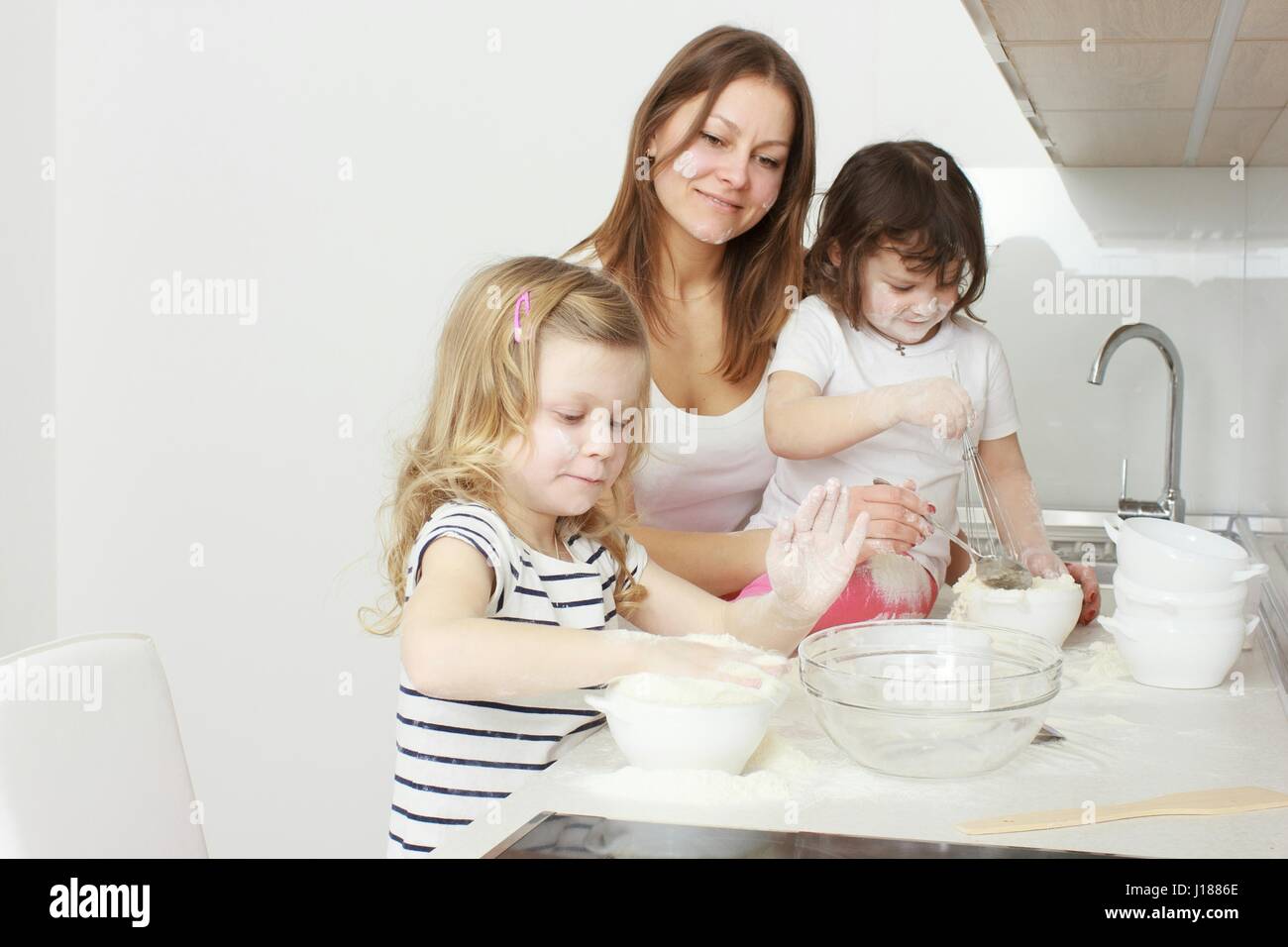 Maman avec ses 5 ans Enfants dans la cuisine maison de gâteau dans la cuisine Banque D'Images