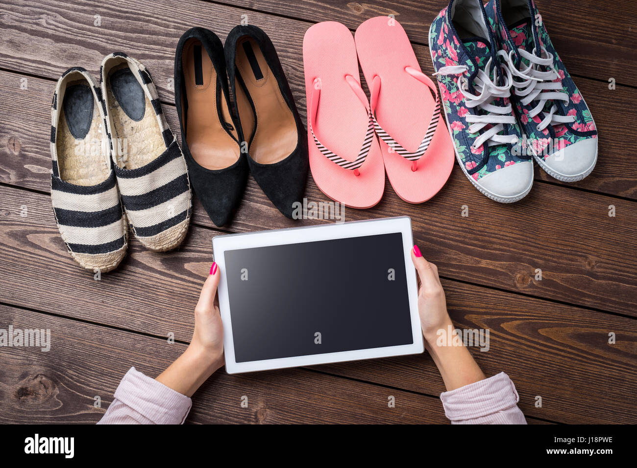 Chaussures femme collection sur table en bois avec white woman's hands holding digital tablet Banque D'Images