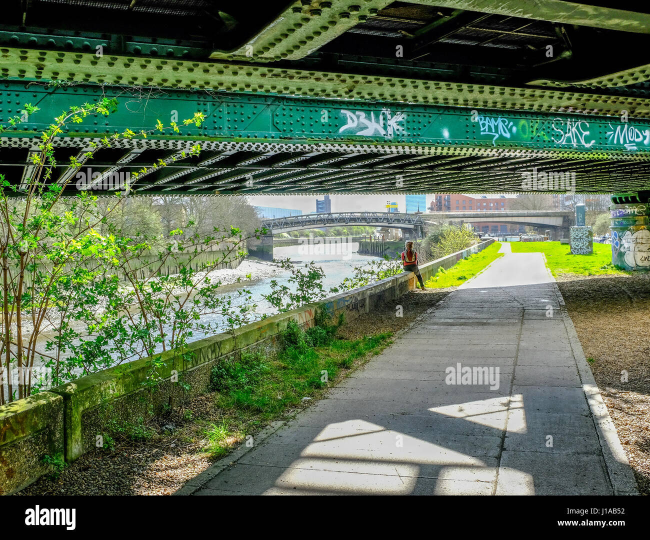 Dame randonneur assis sous un pont de chemin de fer à côté de la rivière Lea dans l'Est de Londres. Banque D'Images