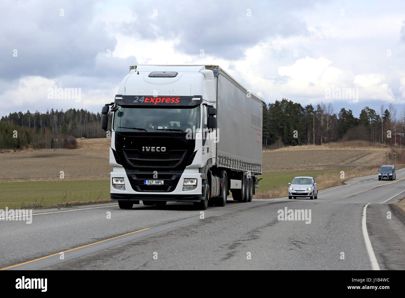 Salo, Finlande - le 13 avril 2017 : blanc iveco stralis hi-way camion semi remorque transporte curtainsider parmi le trafic sur un jour nuageux du printemps. Banque D'Images