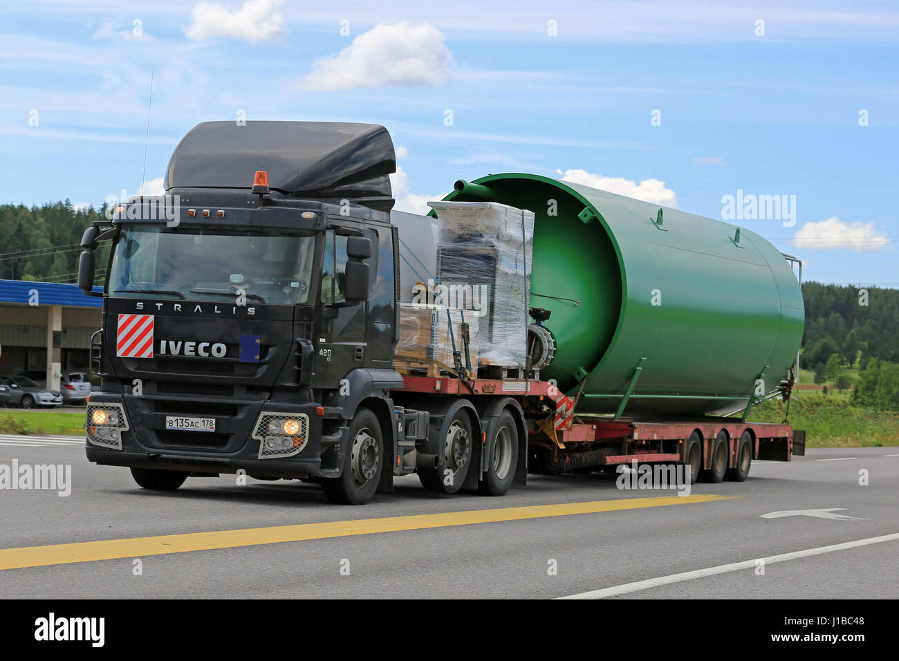 SALO, FINLANDE - le 8 juillet 2016 : Noir 420 camion Iveco Stralis semi transporte un grand objet industriel sur remorque plate le long de la route à l'été. Banque D'Images