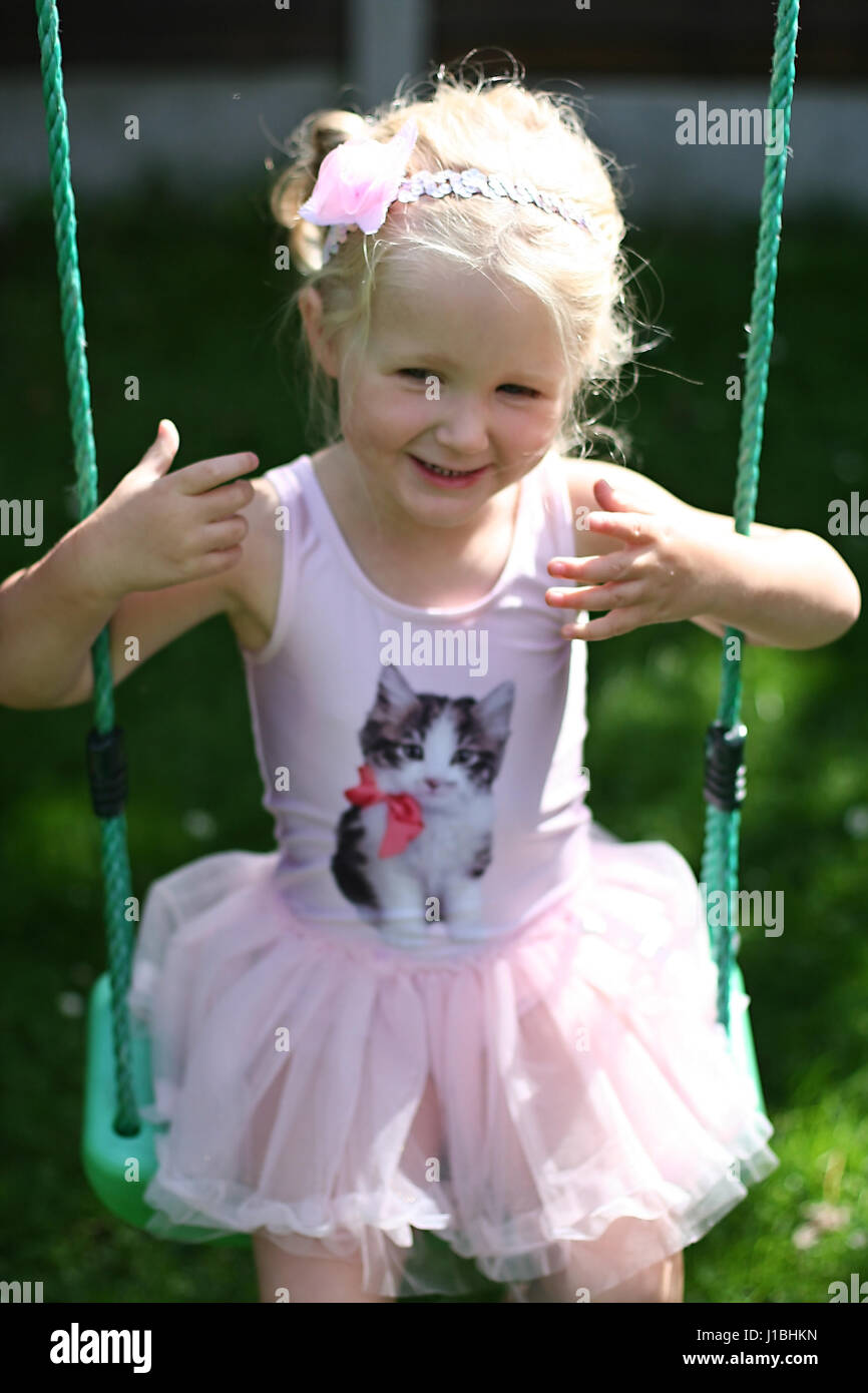 L'enfant blond kid tutu oscillante swing l'été le jardin, de l'enfance, de la liberté, concept sans soucis, temps heureux, le temps de sa vie, la joie, heureux concept Banque D'Images