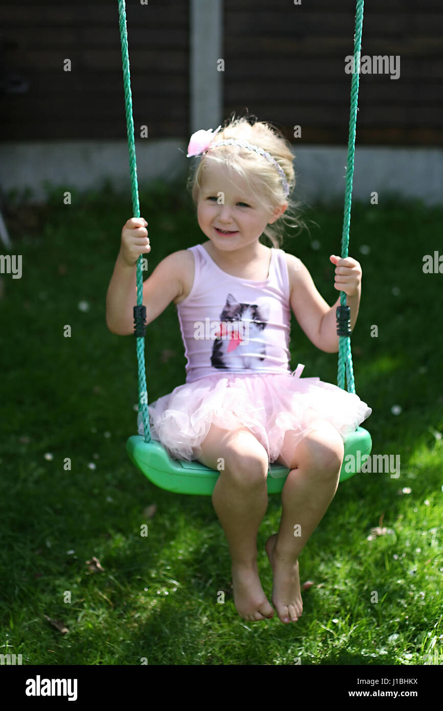 L'enfant blond kid tutu oscillante swing l'été le jardin, de l'enfance, de la liberté, concept sans soucis, temps heureux, le temps de sa vie, la joie, heureux concept Banque D'Images