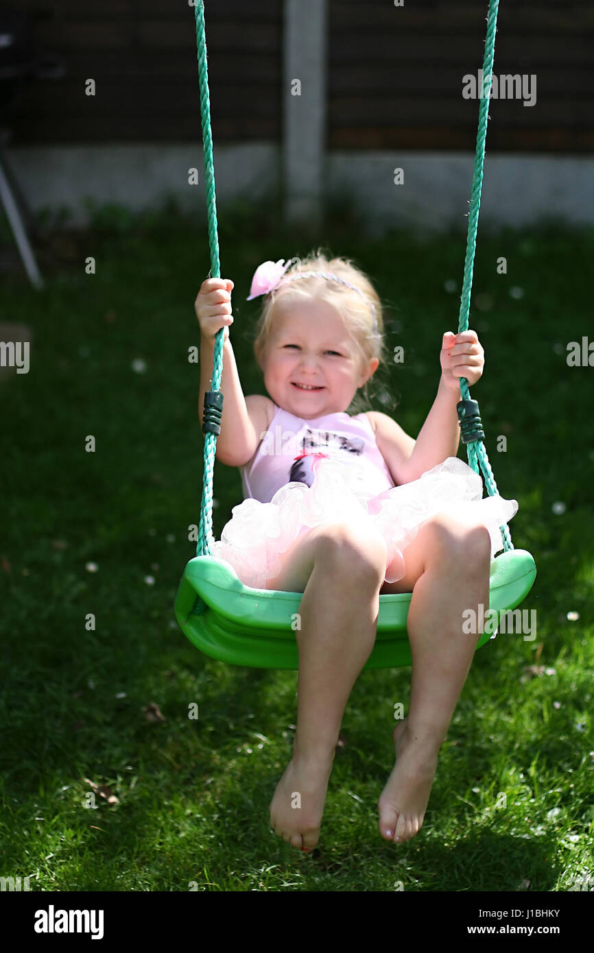 L'enfant blond kid tutu oscillante swing l'été le jardin, de l'enfance, de la liberté, concept sans soucis, temps heureux, le temps de sa vie, la joie, heureux concept Banque D'Images
