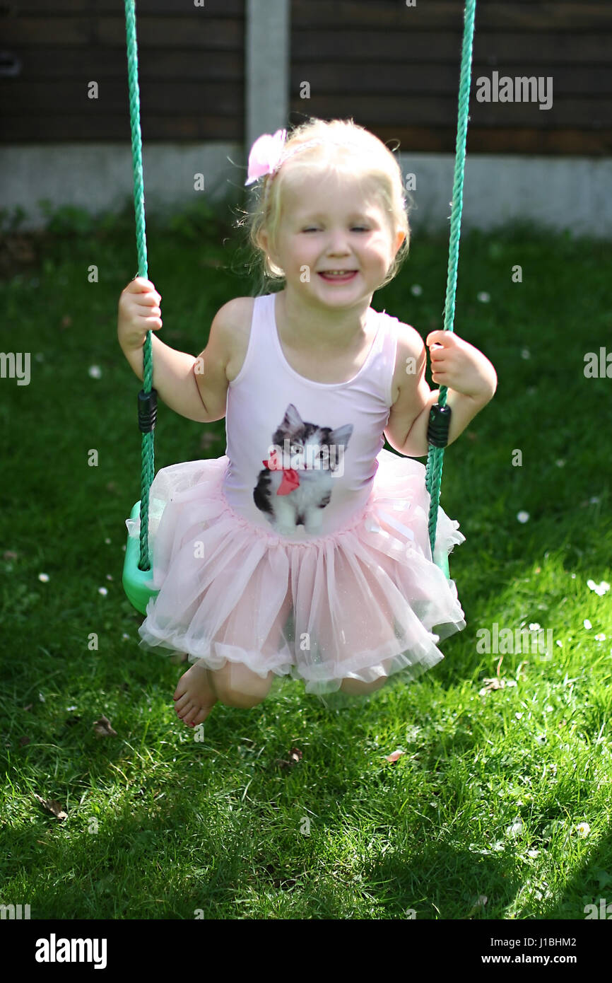 L'enfant blond kid tutu oscillante swing l'été le jardin, de l'enfance, de la liberté, concept sans soucis, temps heureux, le temps de sa vie, la joie, heureux concept Banque D'Images