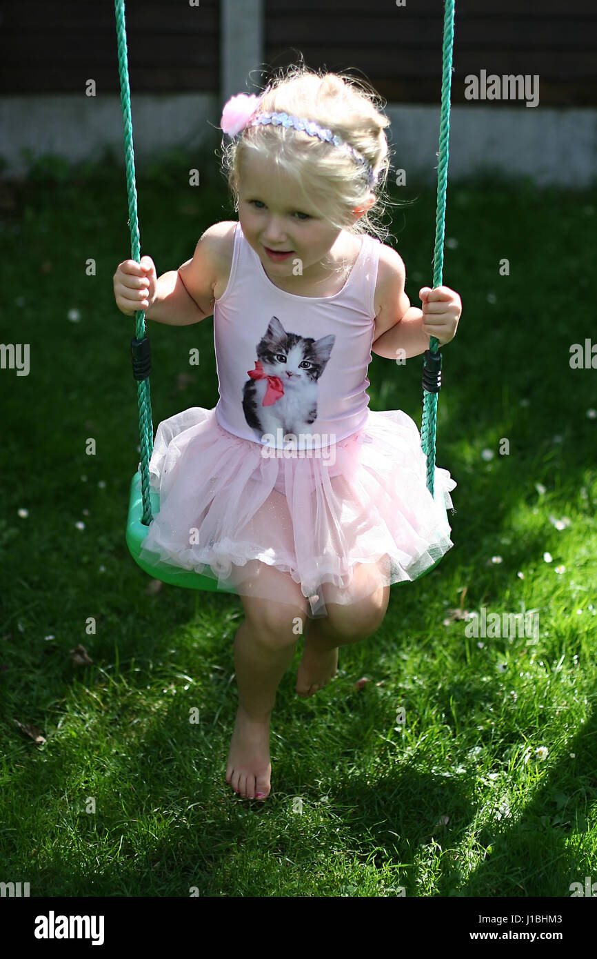 L'enfant blond kid tutu oscillante swing l'été le jardin, de l'enfance, de la liberté, concept sans soucis, temps heureux, le temps de sa vie, la joie, heureux concept Banque D'Images