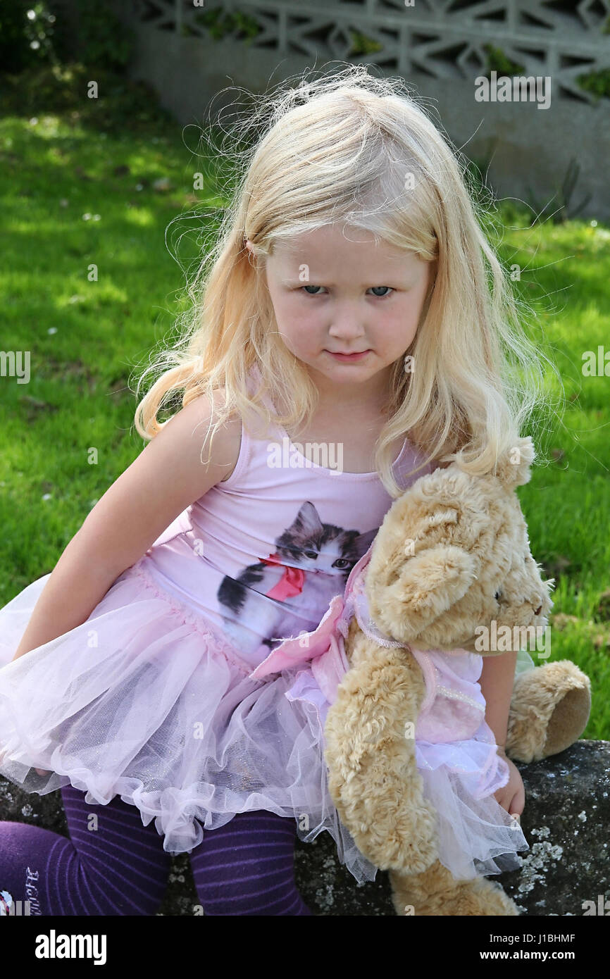 Petite fille blonde, tenant son enfant ours vêtus de tutus correspondant concept tout-petit timide grincheux, petite fille blonde d'été jours curly Banque D'Images