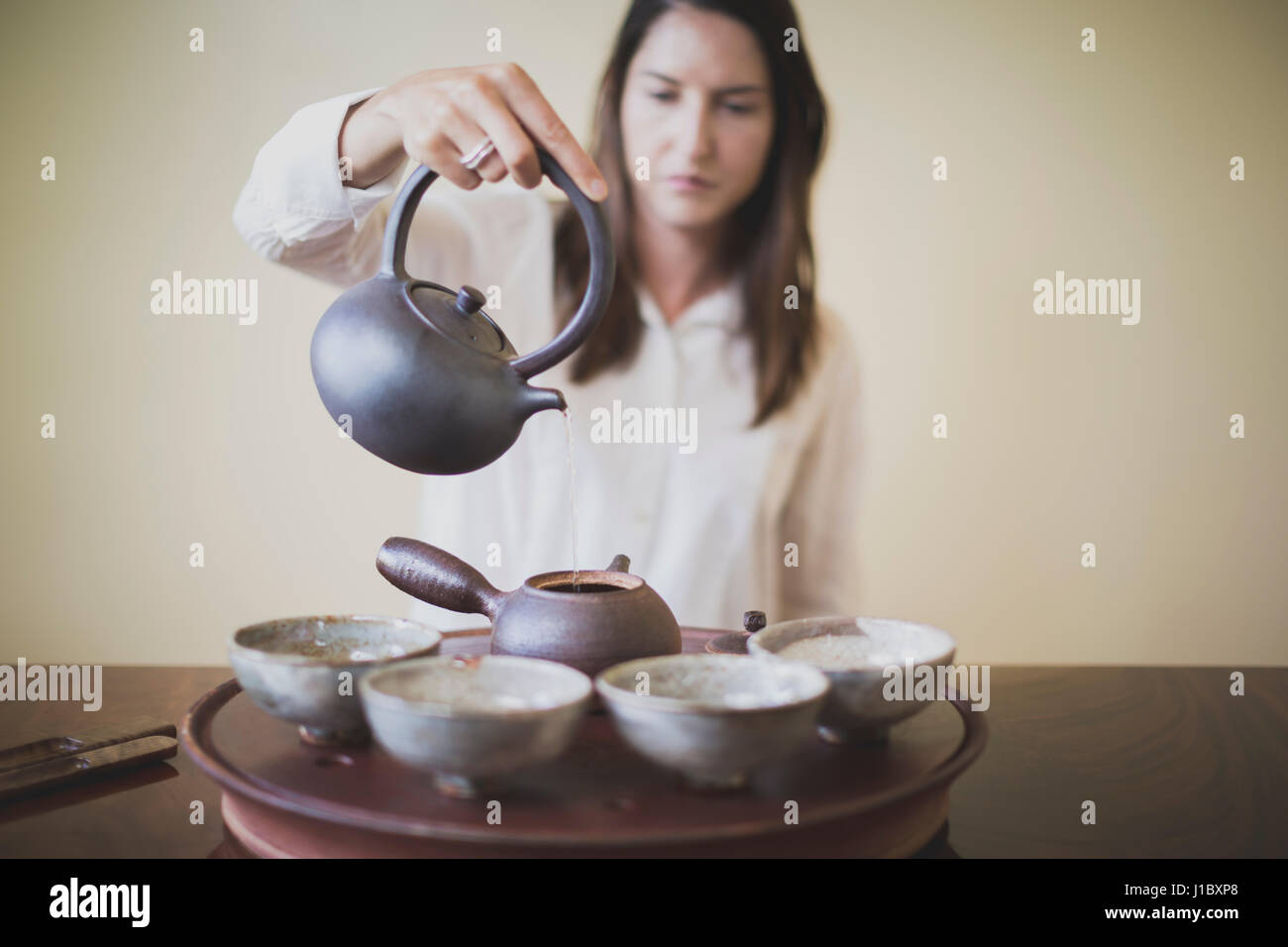 Sarah Hedden pouring tea en céramique tasses à thé sur un plateau. Banque D'Images