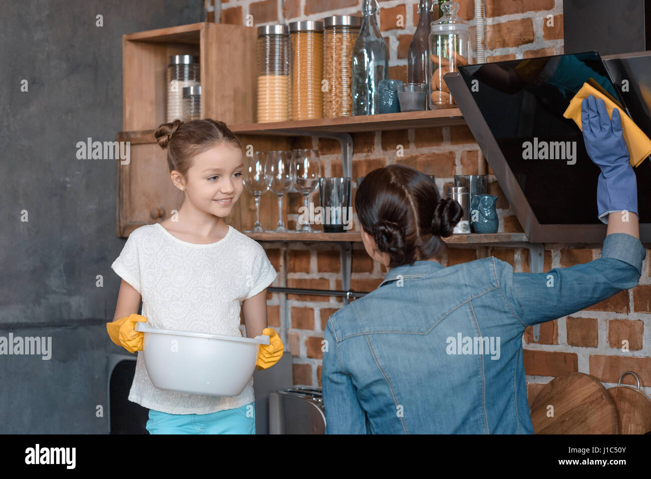 Portrait of smiling fille aider aux travaux ménagers à la maison mère Banque D'Images