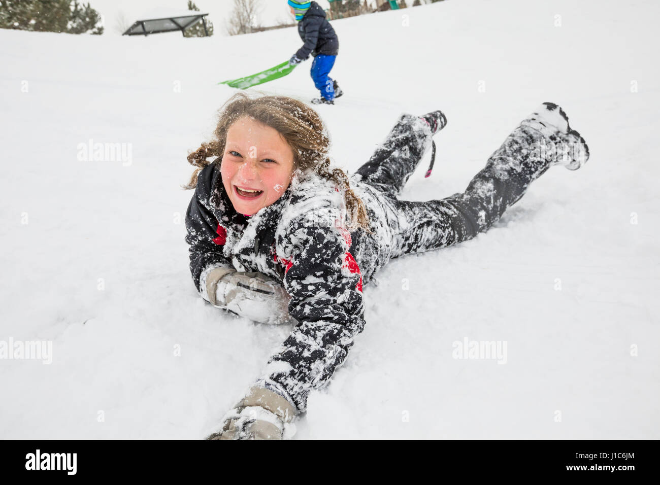 Laughing girl pose dans la neige en hiver Banque D'Images