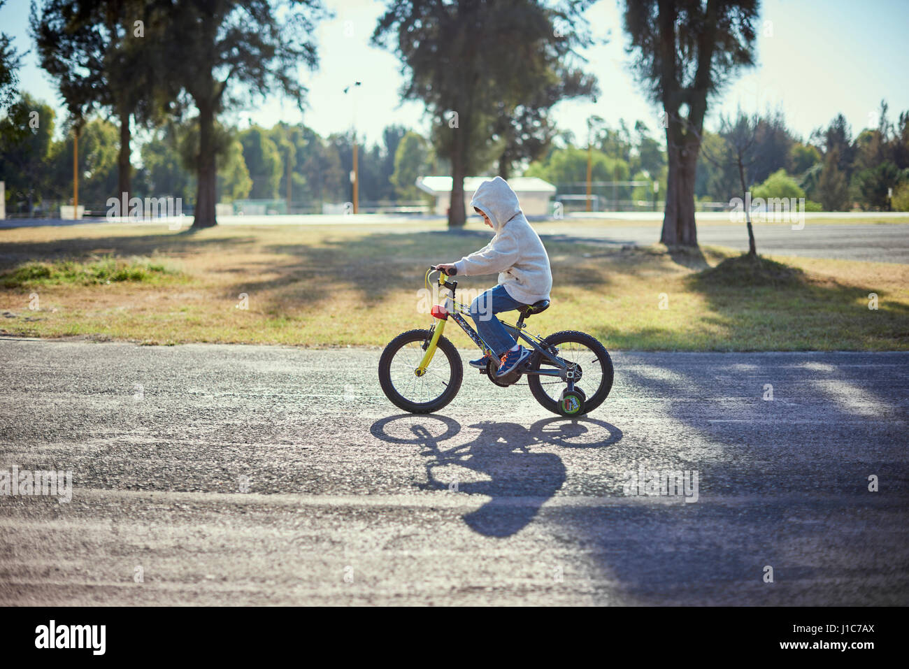 Hispanic boy riding bicycle avec roues de formation Banque D'Images