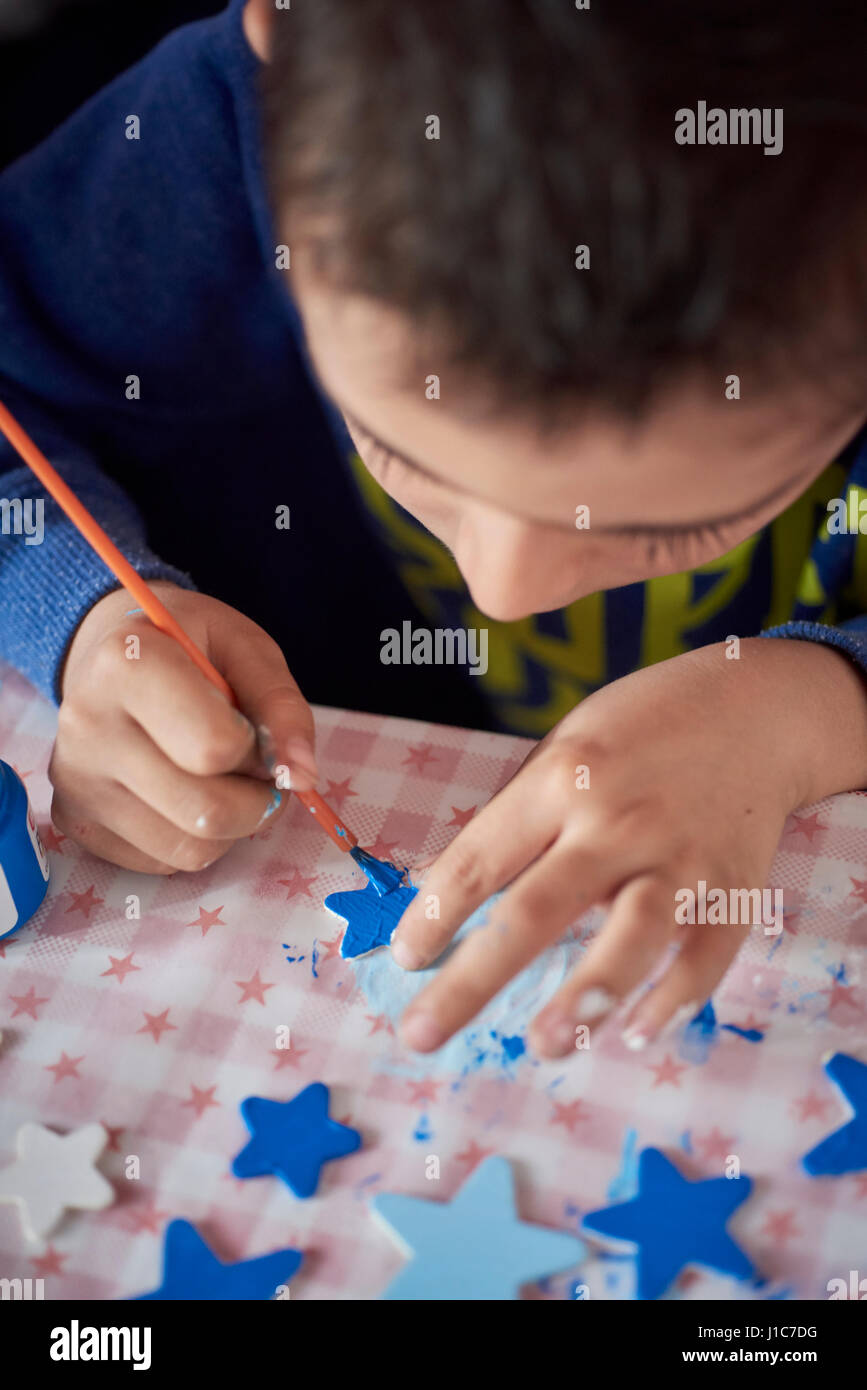 Boy painting stars at table Banque D'Images