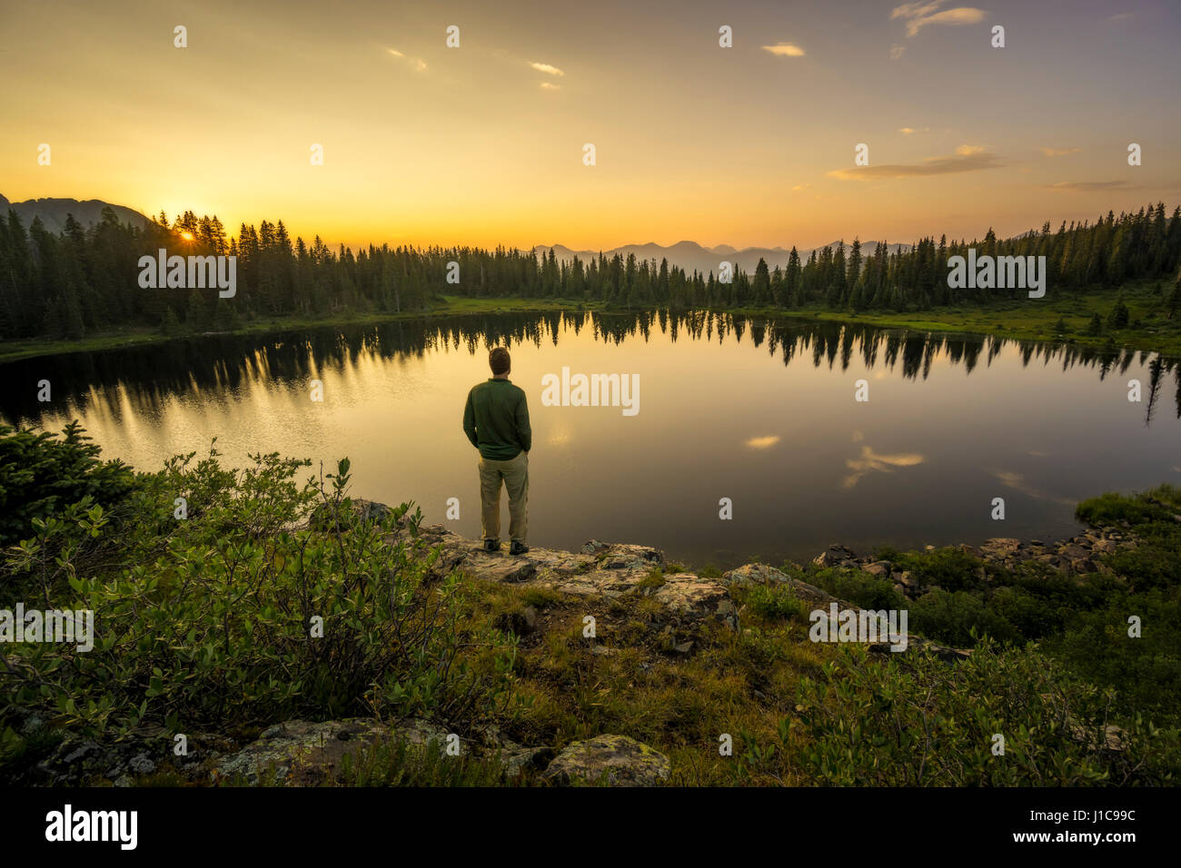 Whit Richardson debout sur affleurement rocheux surplombant le lac du cratère, à l'ouest des montagnes de l'aiguille, au Colorado. Banque D'Images