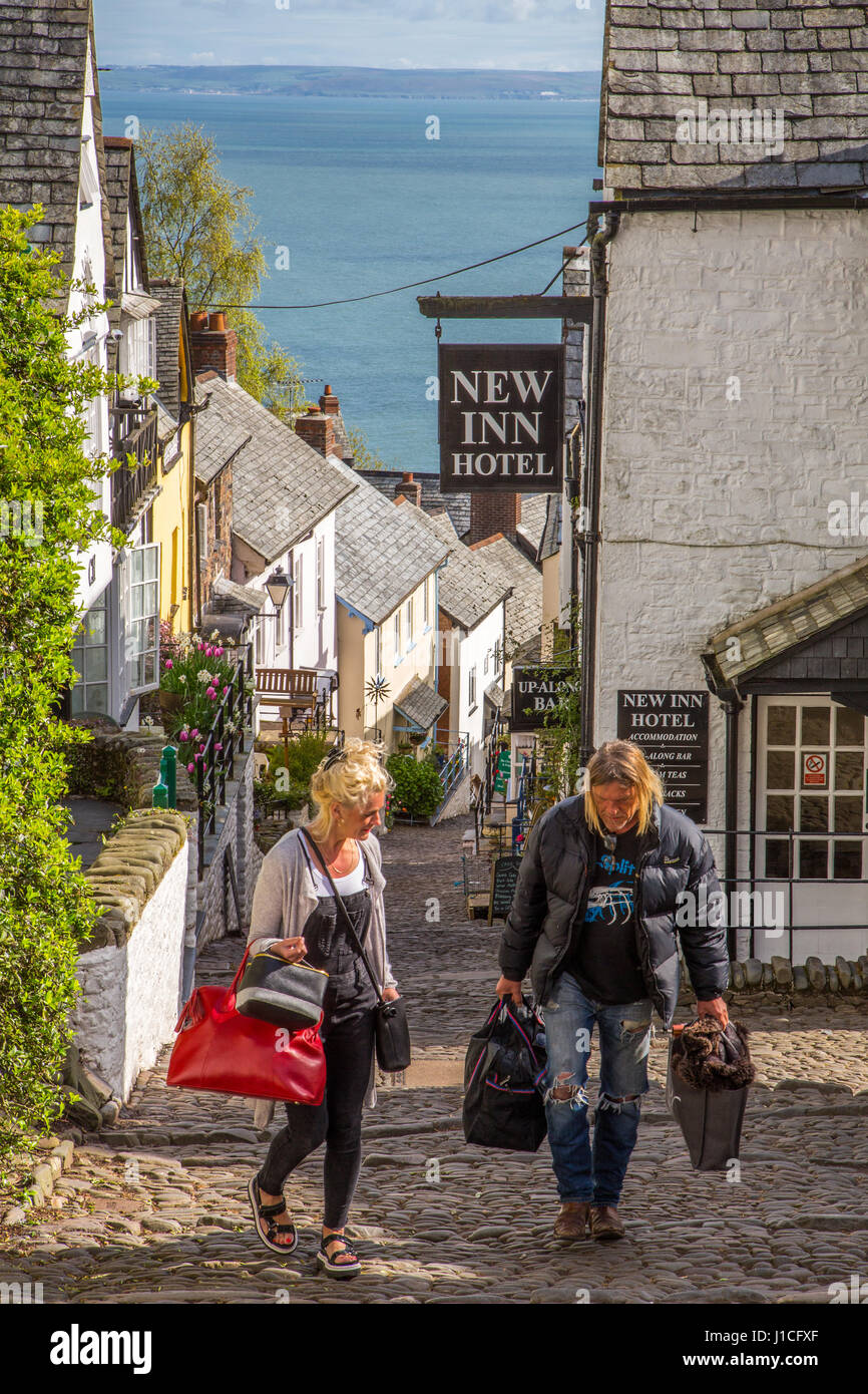 Clovelly,North Devon, UK, les clients avec des valises à monter la rue pavée raide après avoir extrait de The New Inn Hotel Banque D'Images