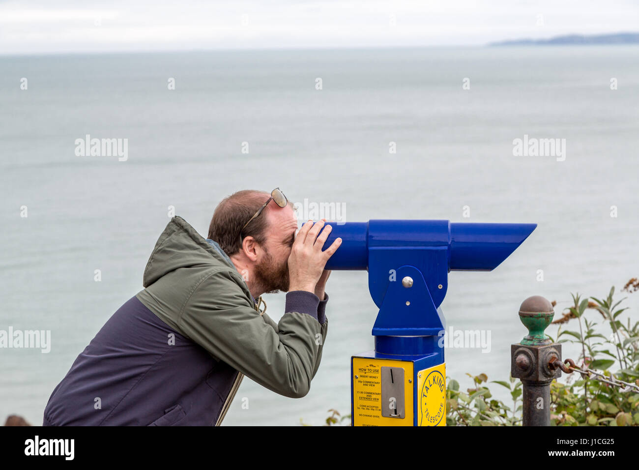 Un homme looking through telescope sur la mer,Devon ,Angleterre,UK Banque D'Images