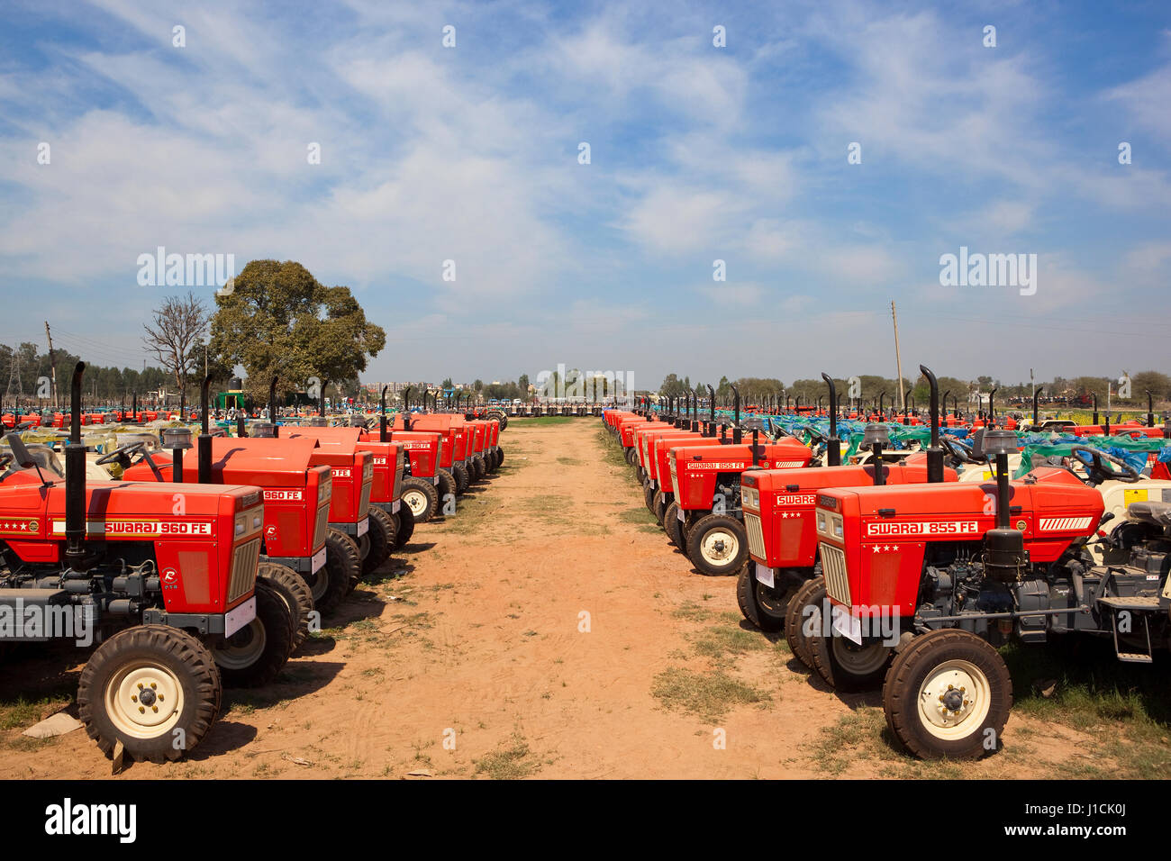Rangées de tracteurs rouges à l'extérieur d'une usine à Chandigarh inde sous un ciel nuageux bleu Banque D'Images