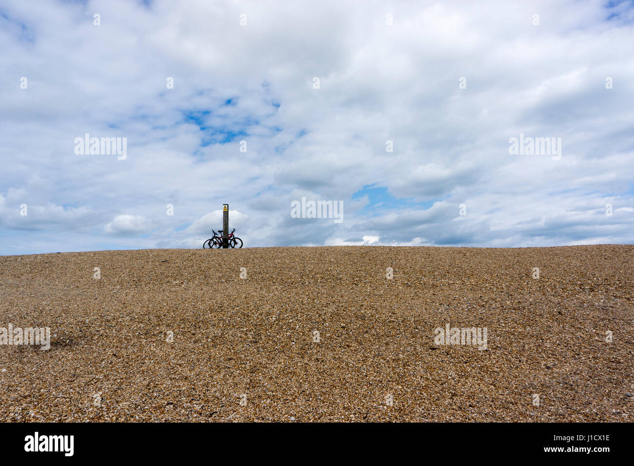 Deux vélos reste contre un poteau sur le bord d'une plage sur Hurst Spit, près de Château de Hurst dans le Hampshire, sur une journée de printemps. Banque D'Images