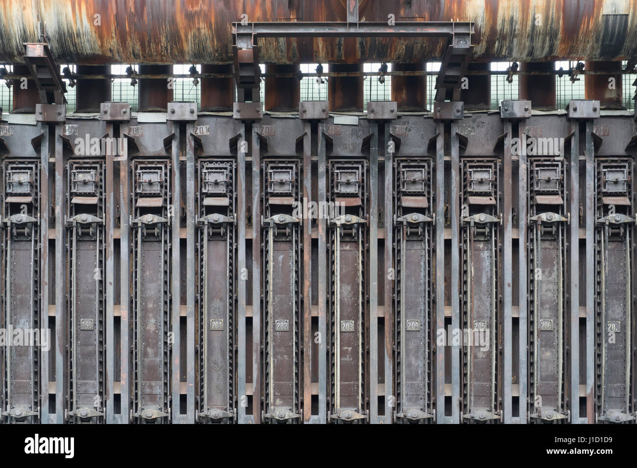 Cette batterie de four à coke appartient comme monument industriel au site du patrimoine mondial de l'UNESCO Zollverein à Essen, en Allemagne. Elle était en production jusqu'en 1996 et était la plus grande usine de cokéfaction du monde à cette époque. Vous avez besoin de 10,500 t de charbon pour produire les 8000 t de coke chaque jour. Le gaz du four à coke a été utilisé pour chauffer le four lui-même et pour chauffer la ville d'Essen. D'autres parties du gaz ont été utilisées dans l'industrie chimique. L'usine a commencé dans les années 1957-1961 avec 192 fours à coke. Plus tard, le nombre est passé à 304. Vous voyez ici les fours avec la gamme de numéros de 198 à 207. Banque D'Images