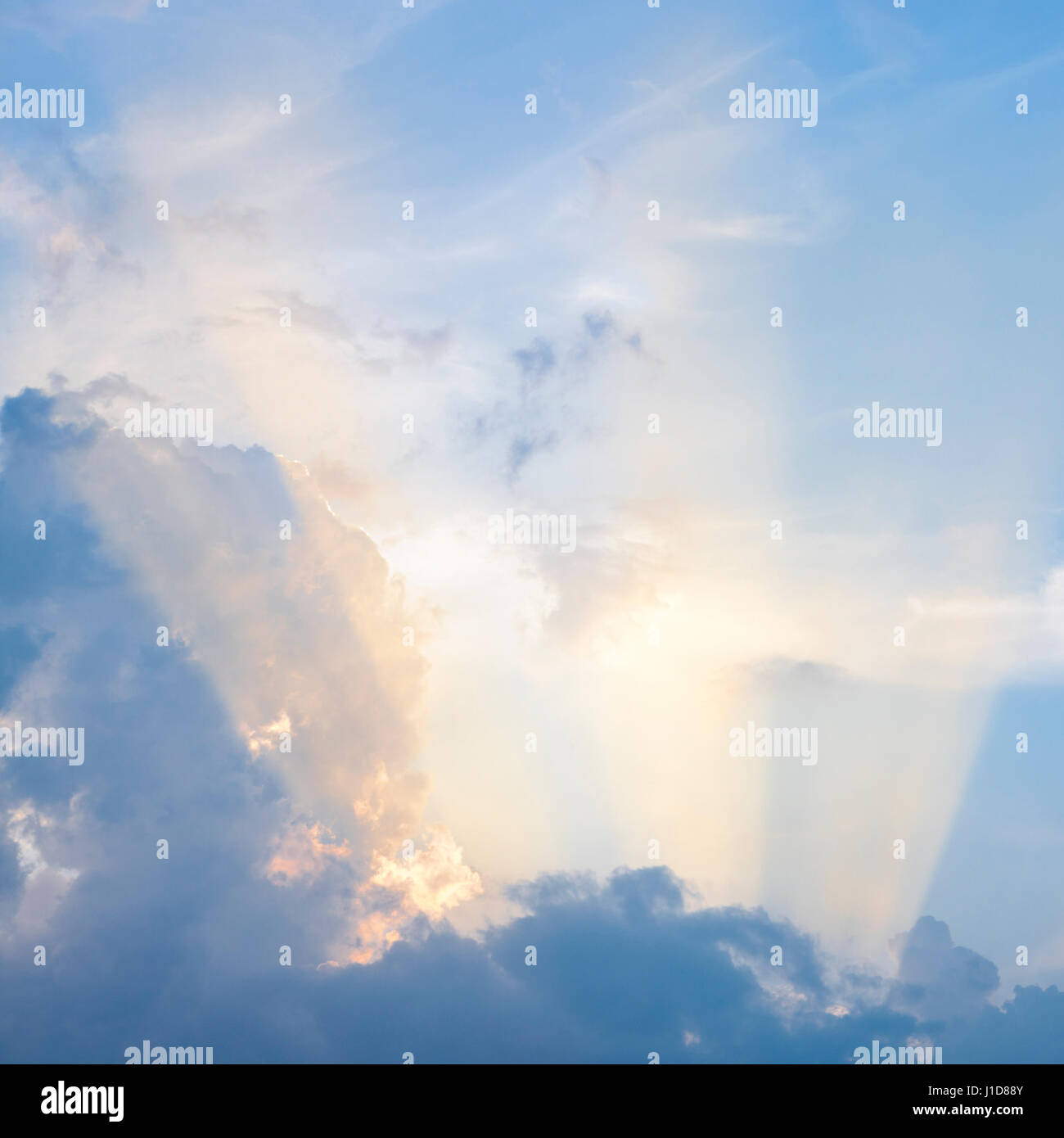 Des faisceaux de lumière du soleil de fin de soirée d'un soleil qui brille à travers les nuages dans le ciel bleu, England, UK Banque D'Images