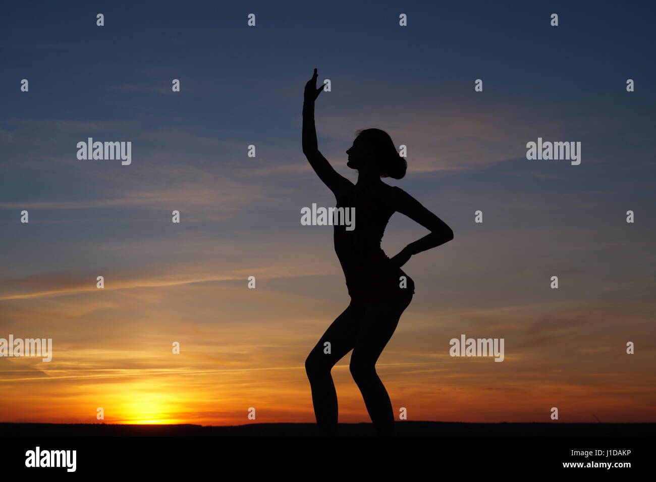 Danseuse dans la dance ne le divise dans l'air contre le coucher du soleil Banque D'Images