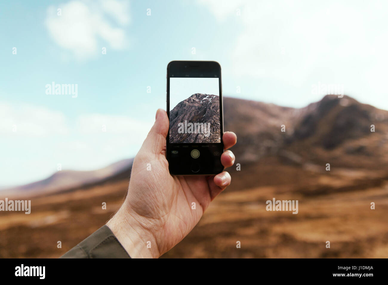 L'homme de prendre des photos avec camera phone in Glencoe Ecosse. Scottish Highlands Banque D'Images