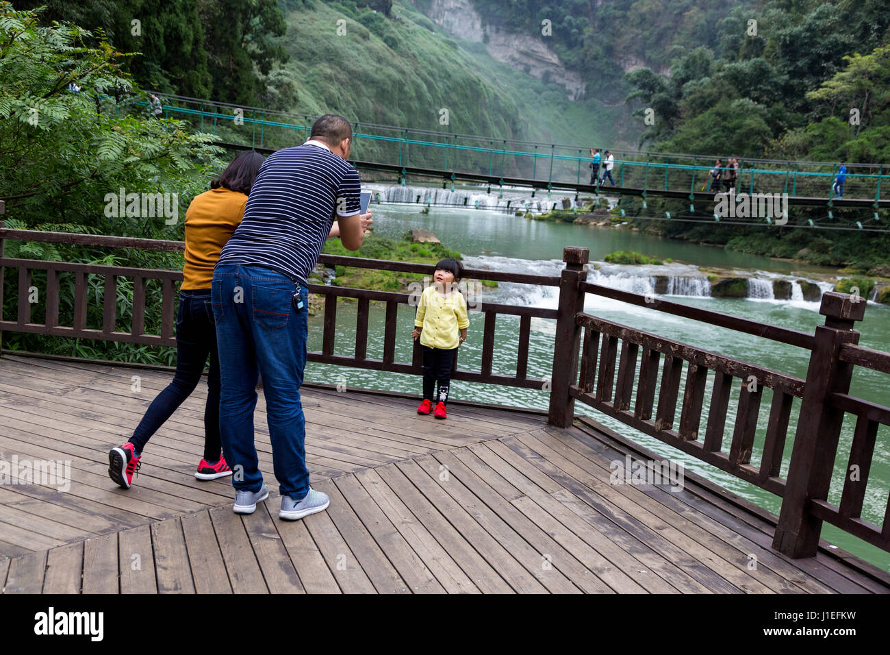 La province du Guizhou, en Chine. Les parents photographiant leur fille à fruit jaune (arbre) Huangguoshu Waterfall Scenic Area. Banque D'Images