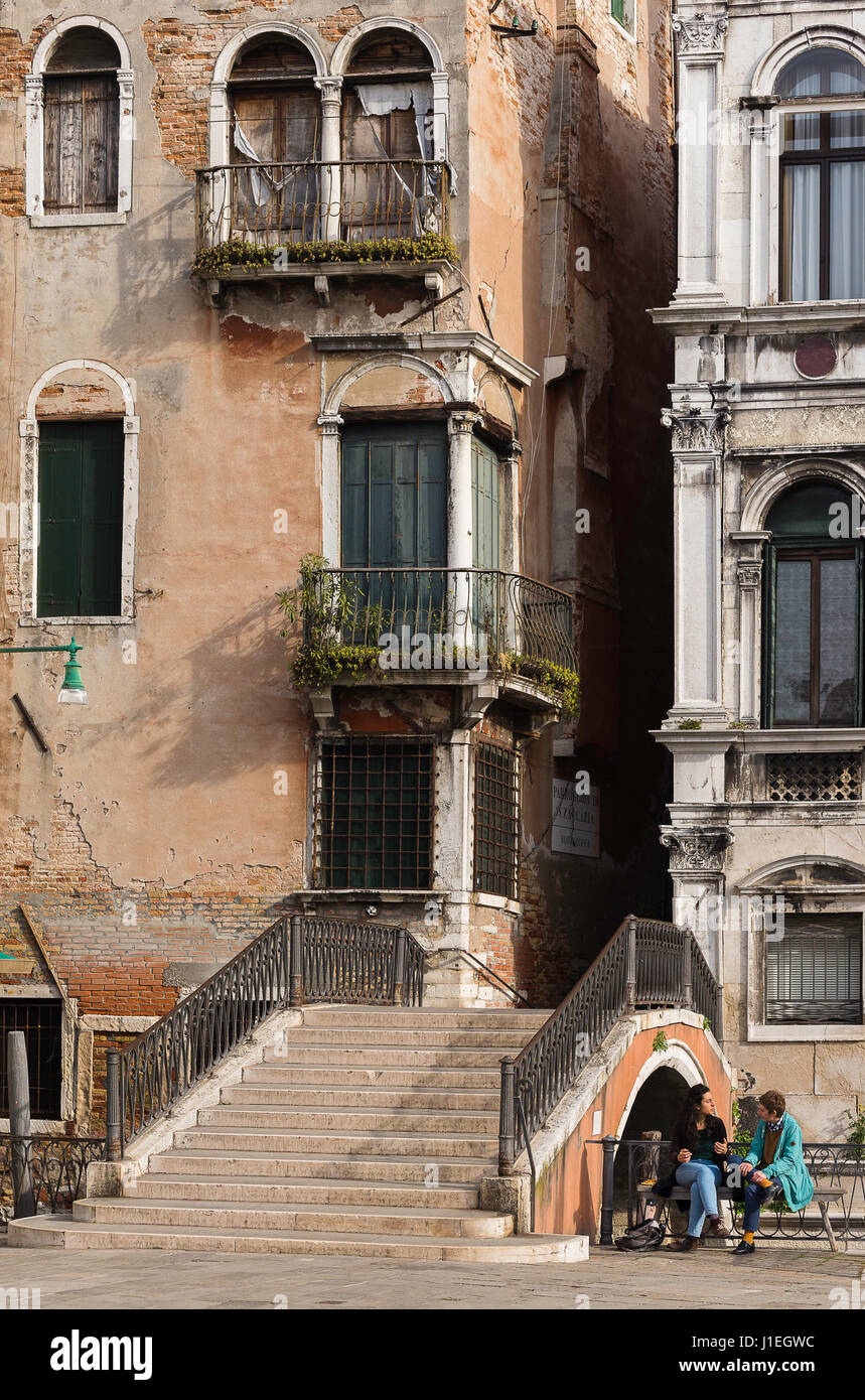 Deux dames assis sur un côté du canal parle banc à côté d'un pont, Venise, Italie Banque D'Images