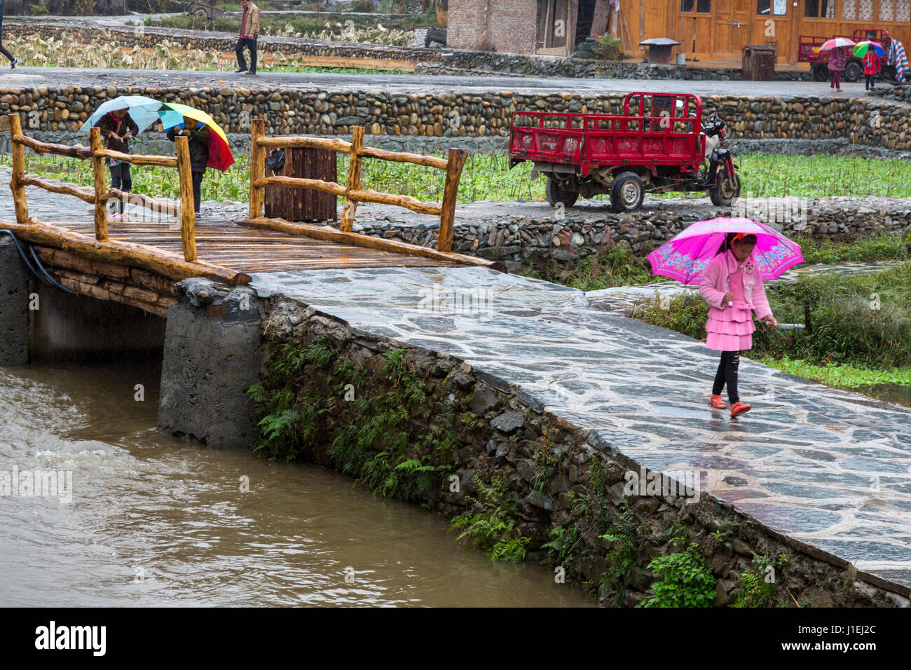 Huanggang, Guizhou, en Chine. Un village ethnique. Enfants Dong à la maison sous la pluie. Banque D'Images