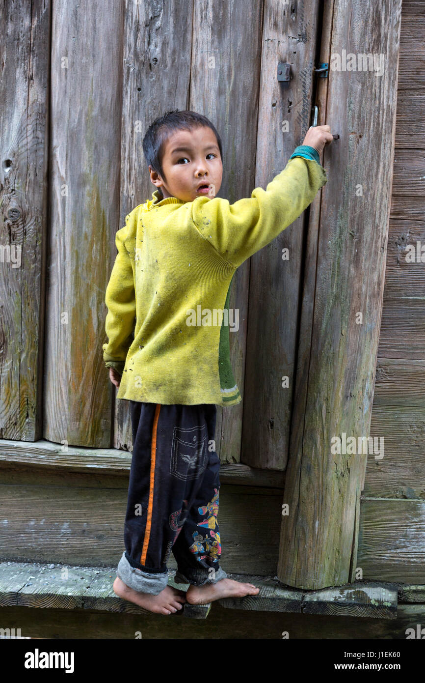 Huanggang, Guizhou, en Chine. Un village ethnique. Petit garçon à la porte d'une maison. Banque D'Images
