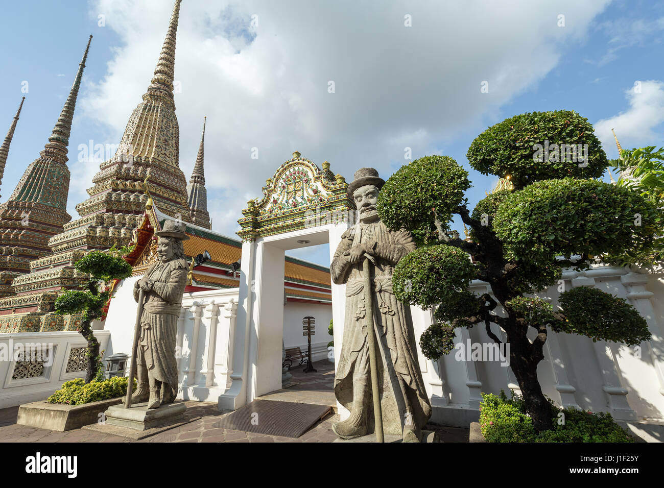 Deux grandes statues, arbres, chinois et porte à l'chedis Wat Pho (Po) complexe des temples de Bangkok, Thaïlande. Banque D'Images
