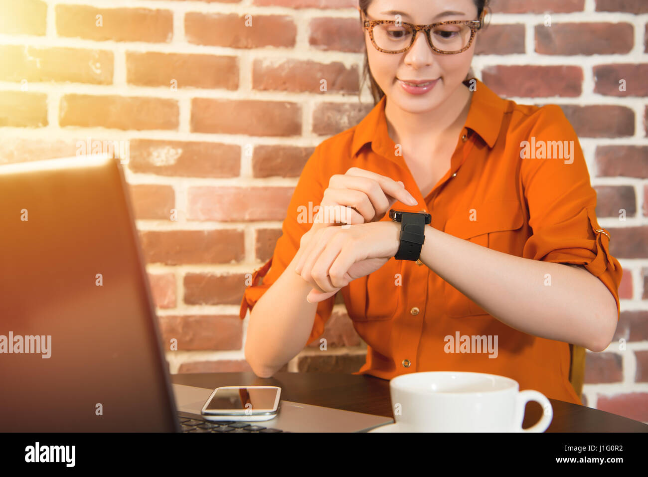 Woman's hands touching smart watch sur la main et téléphone mobile, tasse de café sur la table en bois au café. race mixte modèle chinois asiatique Banque D'Images