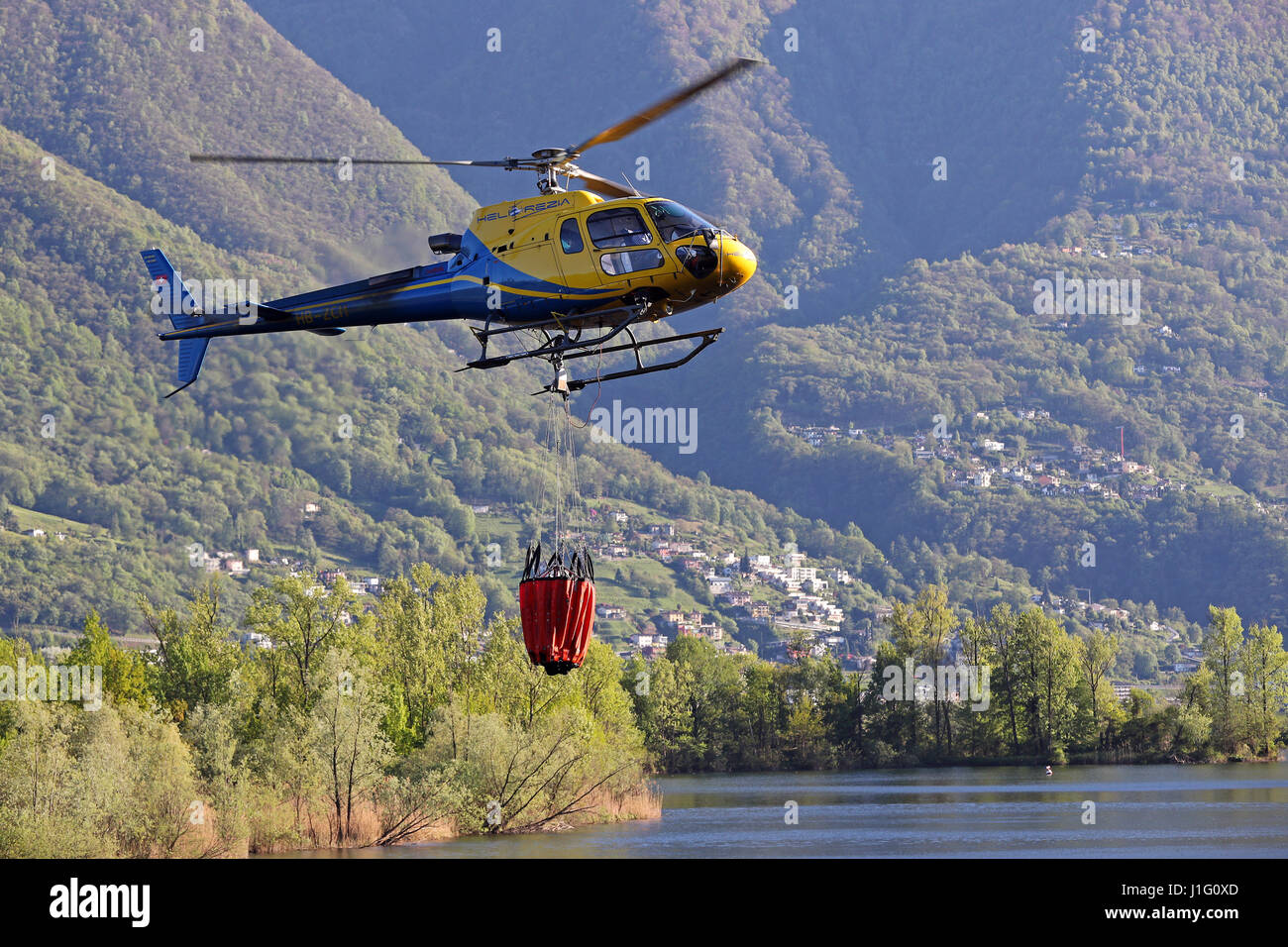 Les efforts de lutte contre l'incendie sont en cours avec des hélicoptères pour éteindre les incendies de forêts au-dessus de Gordola, Tessin, Suisse, le 19 avril, 2017 Banque D'Images