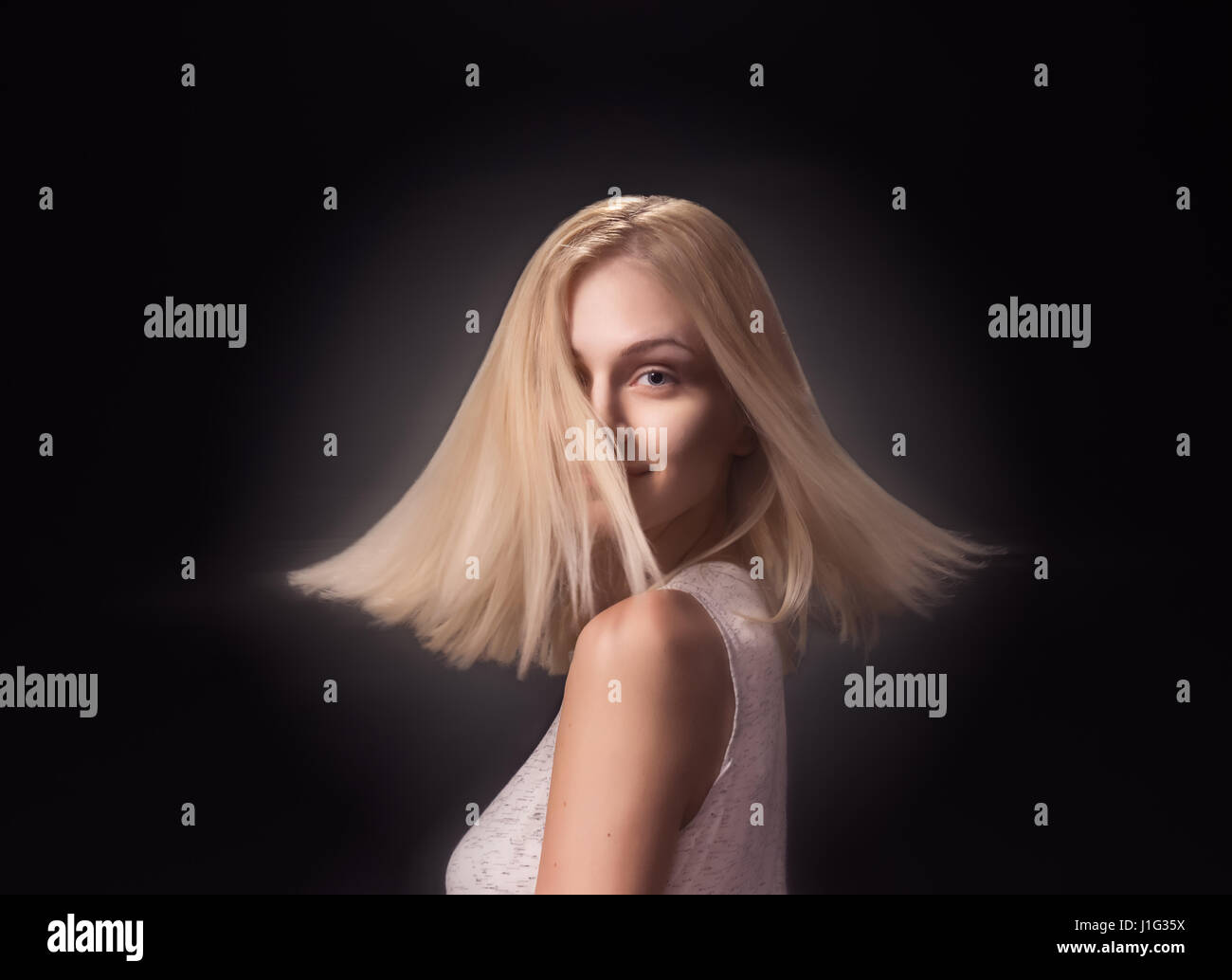 Jeune fille femme adultes, 19 Modèle de mode tournant rotation tête visage cheveux blonds. Fond noir studio Banque D'Images