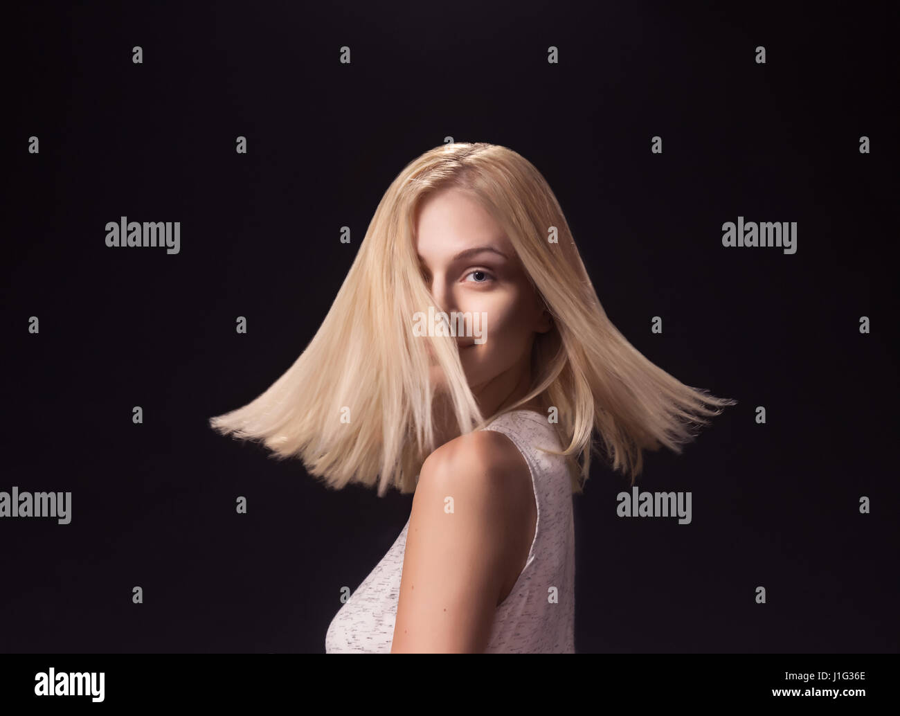 Jeune fille femme adultes, 19 Modèle de mode tournant rotation tête visage cheveux blonds. Fond noir studio Banque D'Images