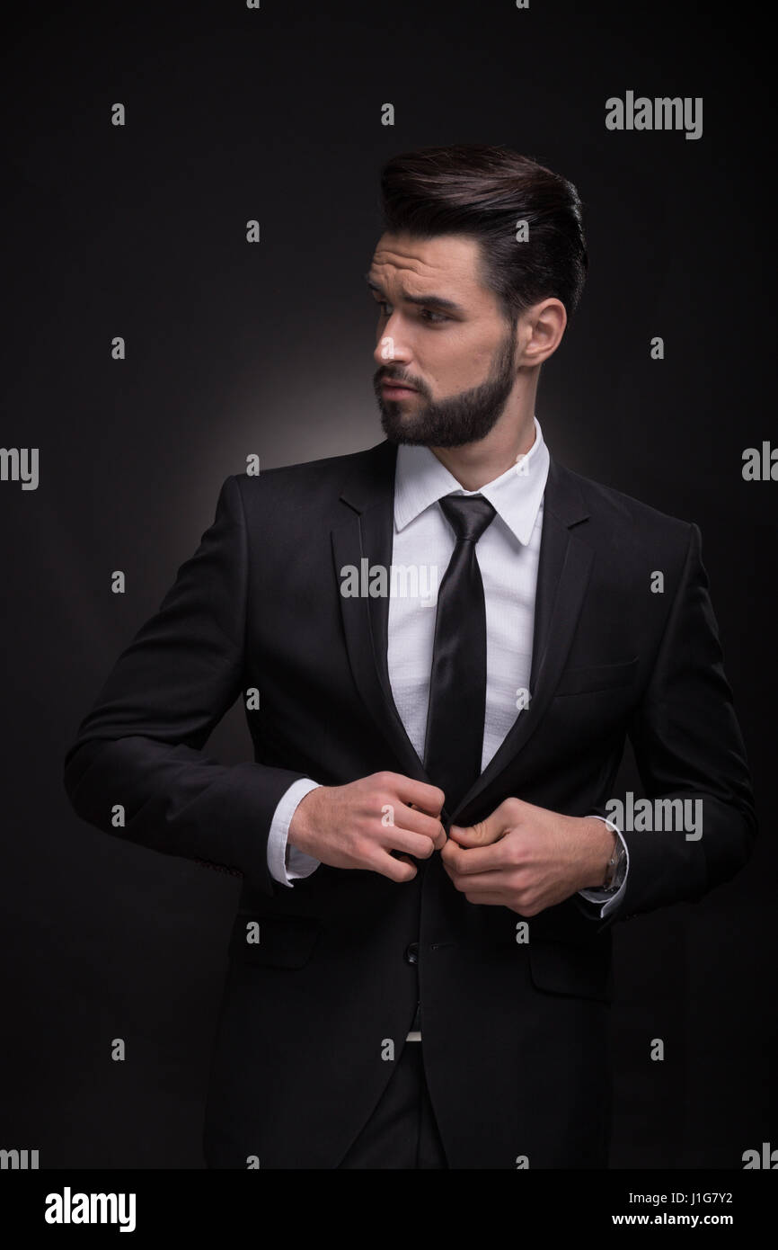 Un jeune homme beau costume élégant, à la hiérarchie, à l'arrière-plan noir,  Costume noir chemise cravate Photo Stock - Alamy
