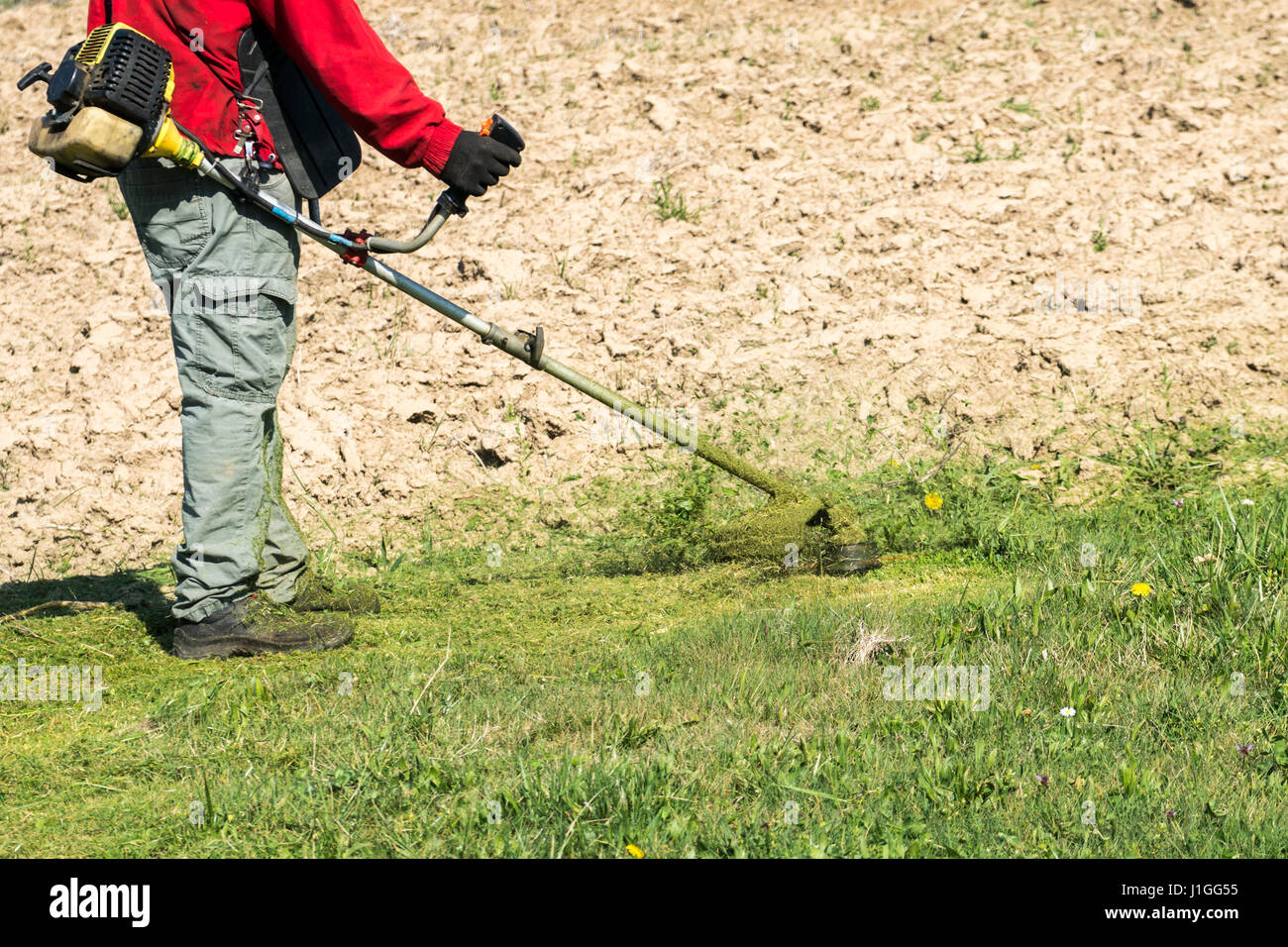 Travailleur masculin avec chaîne d'outils de jardin tondeuse à gazon Tondeuse à gazon jardin Banque D'Images