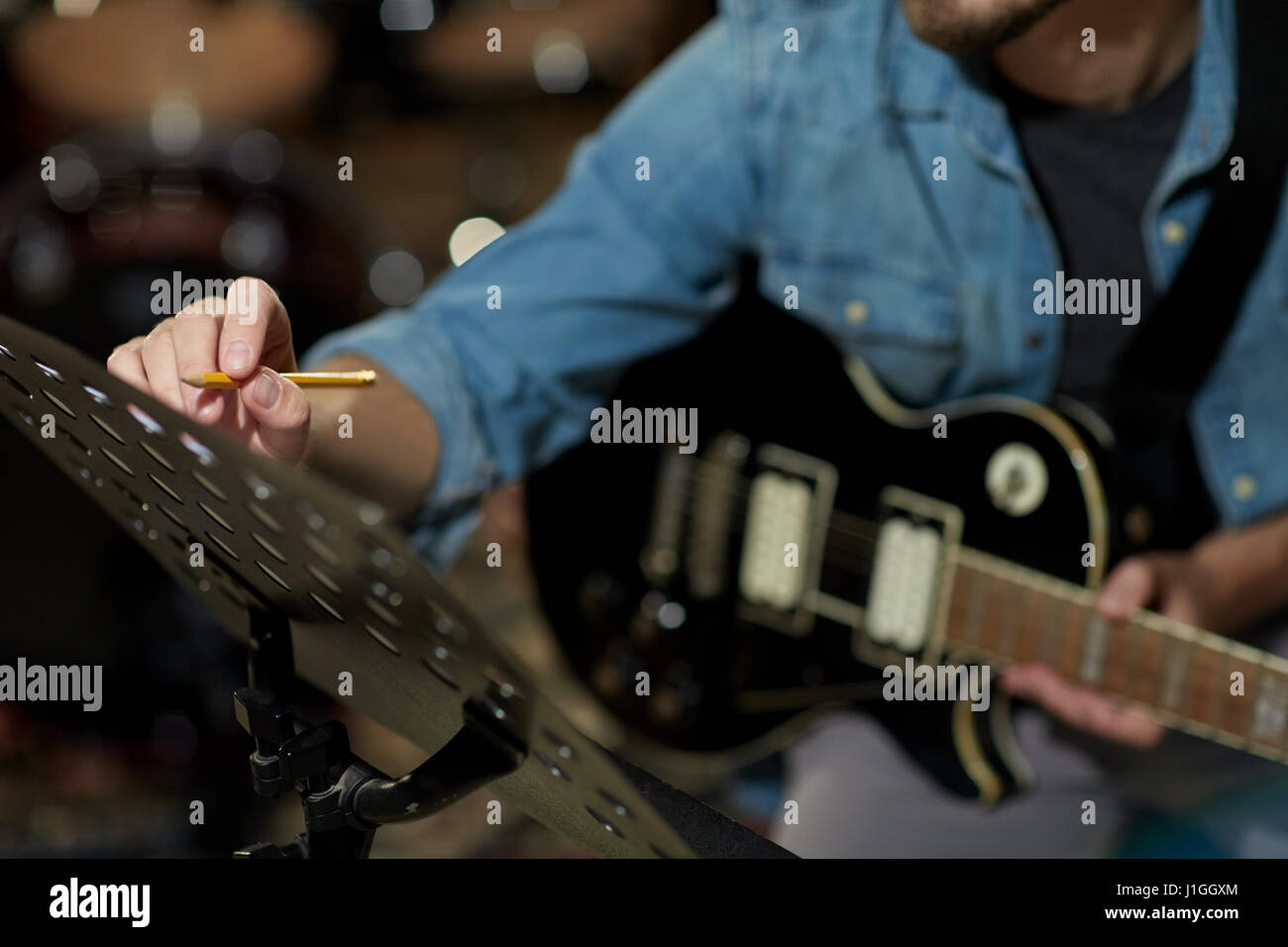 Man with guitar écrit au livre de la musique au studio Banque D'Images
