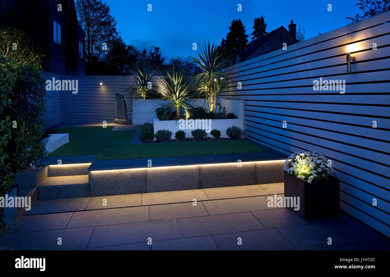 Jardin anglais contemporain moderne avec sol en bois peint clôture écran prévu, faux gazon et pavage de granit Banque D'Images