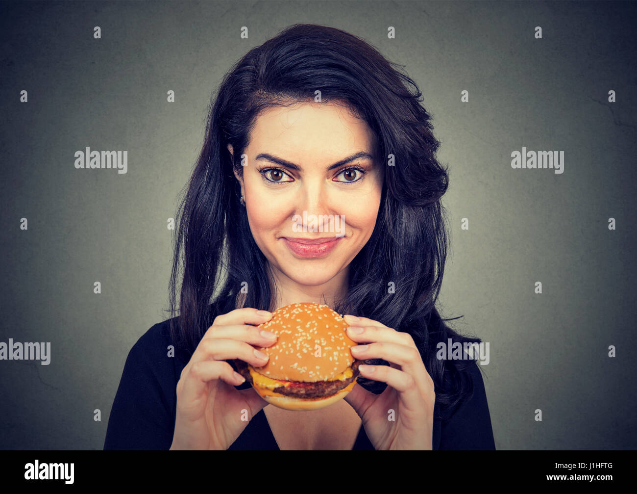 Woman eating burger en souriant. Beau modèle féminin Banque D'Images