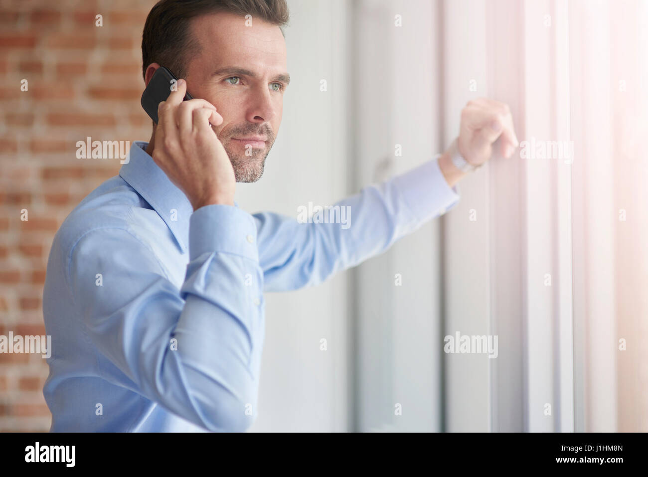 Businessman with phone s'appuyant sur la fenêtre Banque D'Images