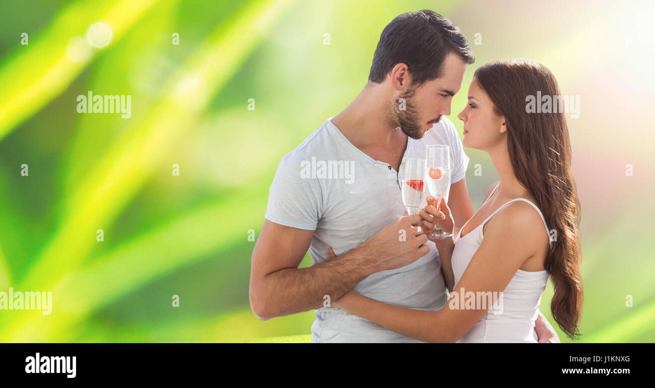 Passionné de couple holding champagne flutes tout en embrassant sur arrière-plan flou Banque D'Images